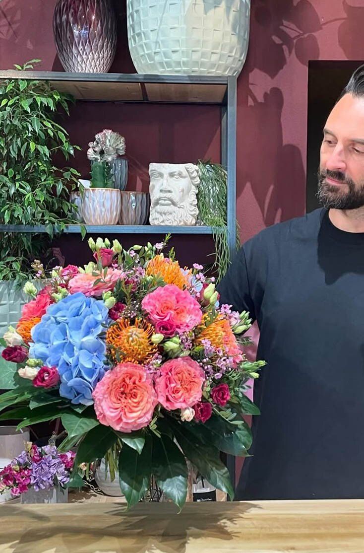 Paolo di FLORA Ticino con un bouquet di ortensie e rose in boutique
