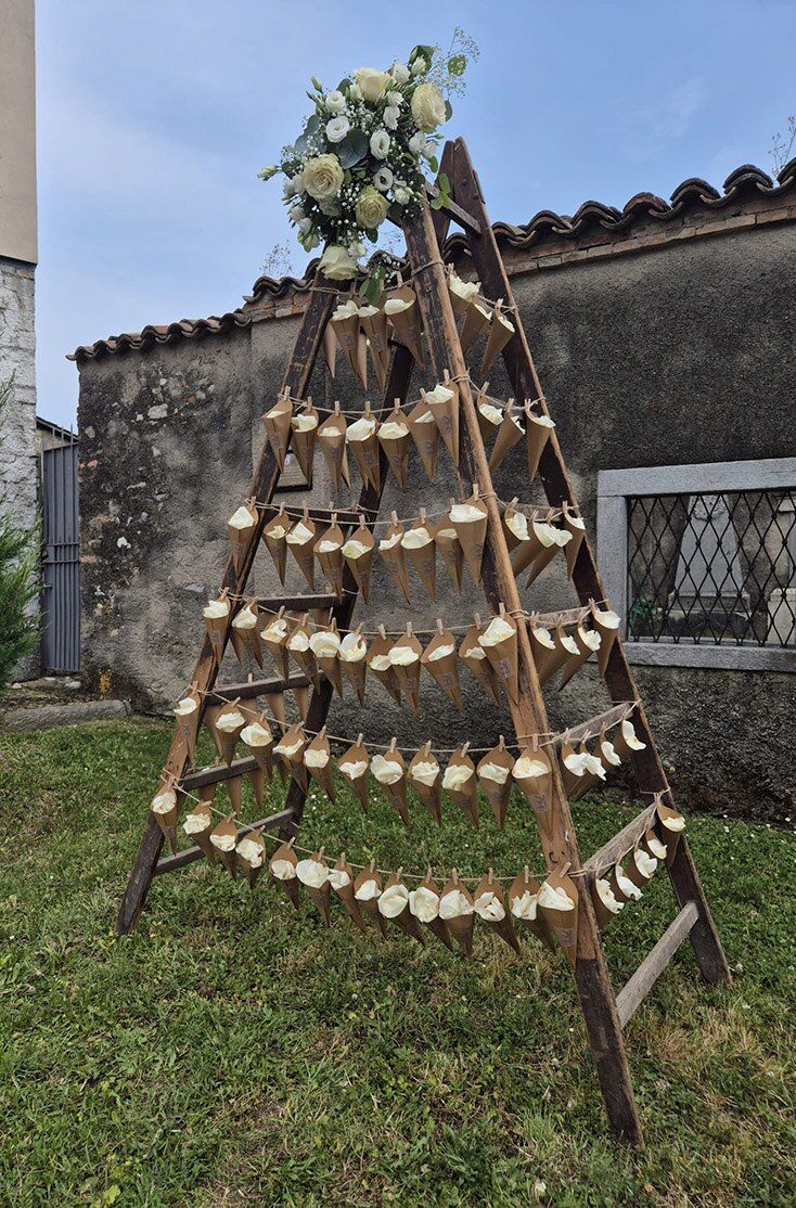 Scala in legno decorata con fiori e bottiglie per un matrimonio all’aperto